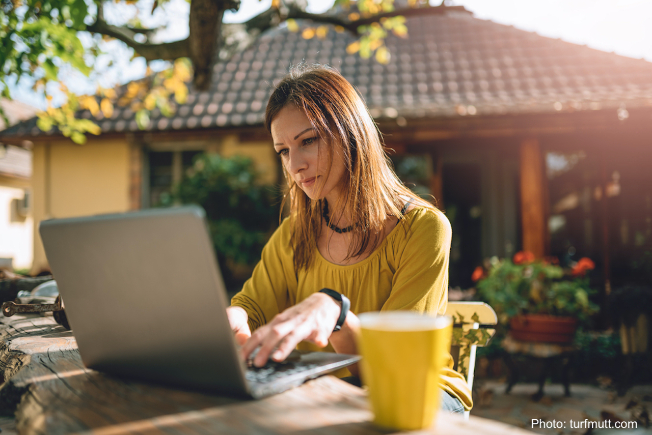 Femme travaillant sur un ordinateur sur une table sur la terrasse.