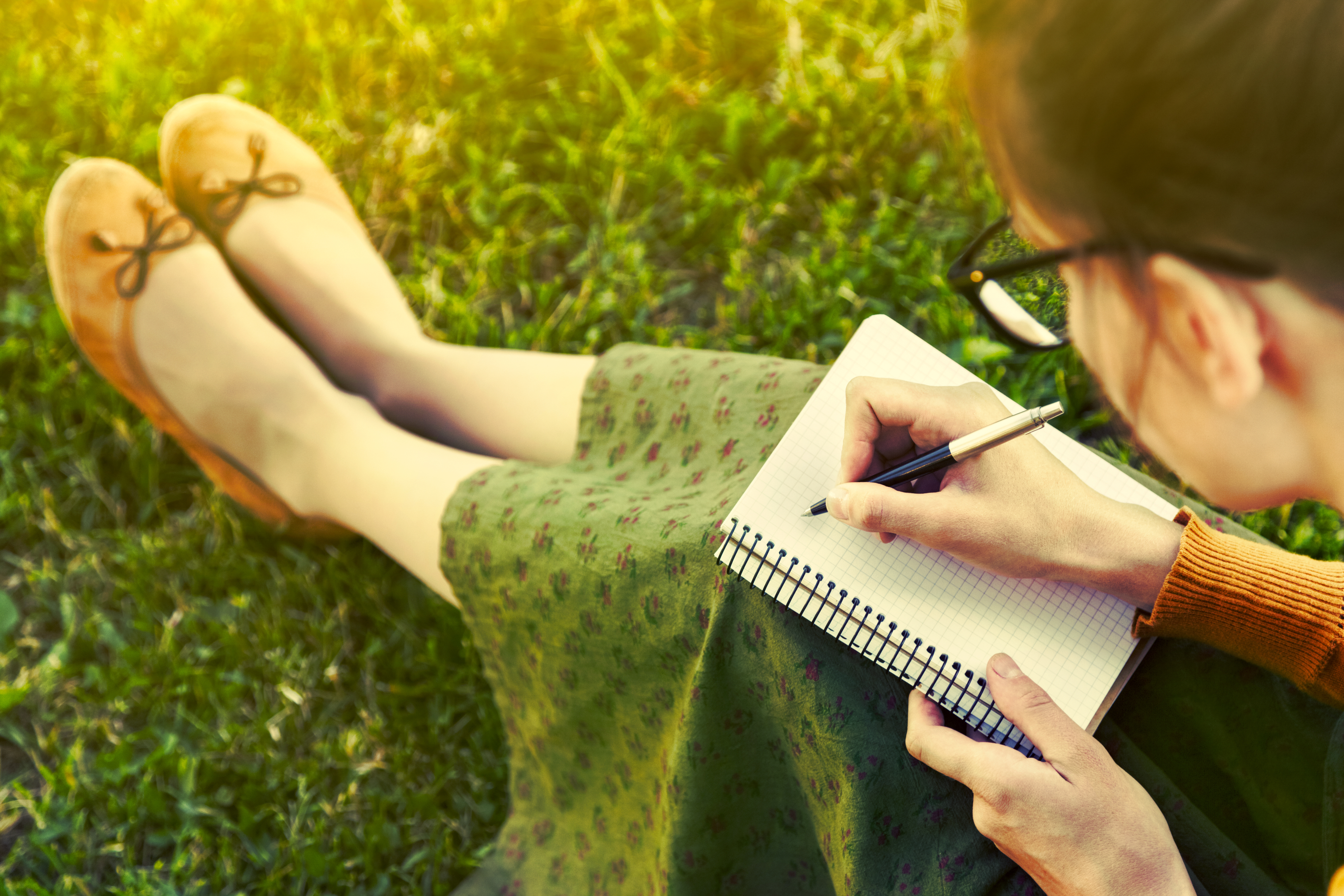 Femme écrivant dans un carnet sur la pelouse