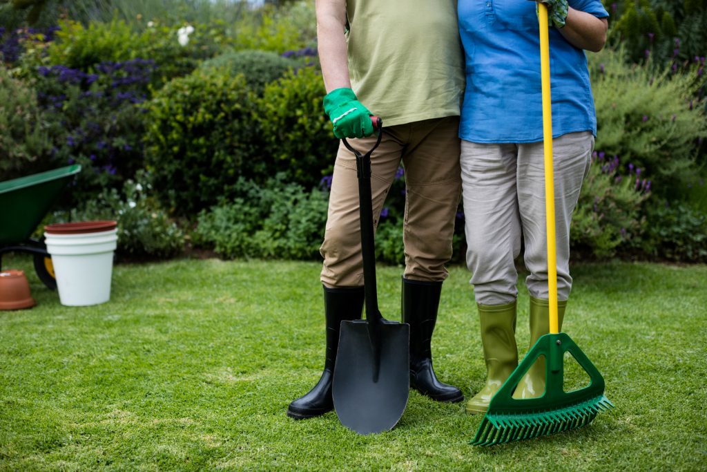 Couple debout sur une pelouse avec des outils de rénovation.