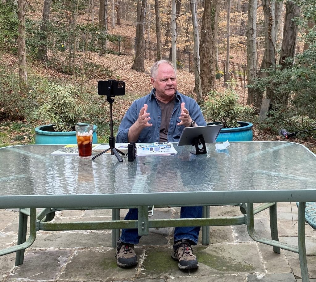 Homme travaillant à ce bureau en plein air avec un boisé en arrière-plan.