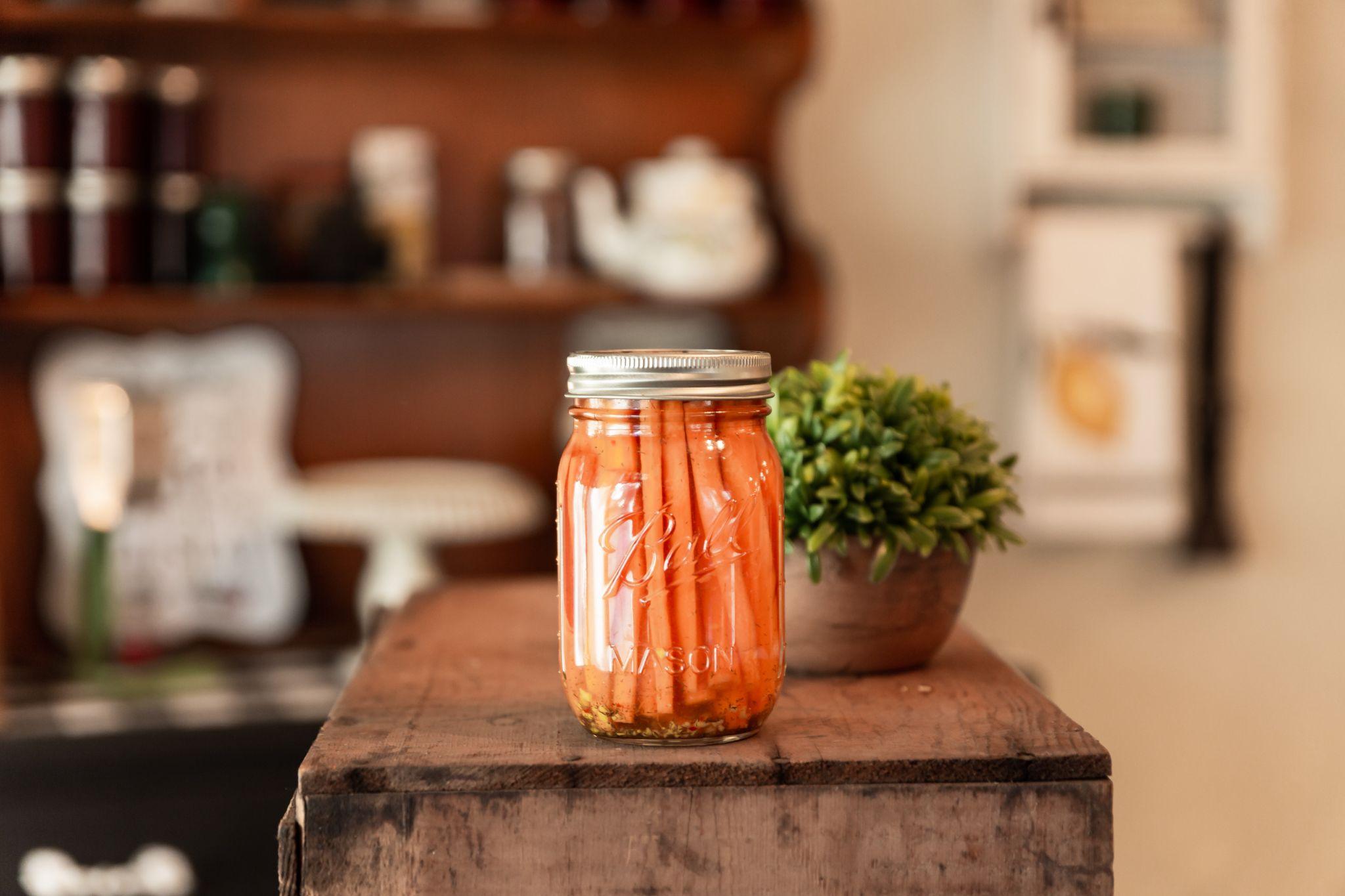 Pot Mason contenant des bâtonnets de carottes sur un comptoir en bois.